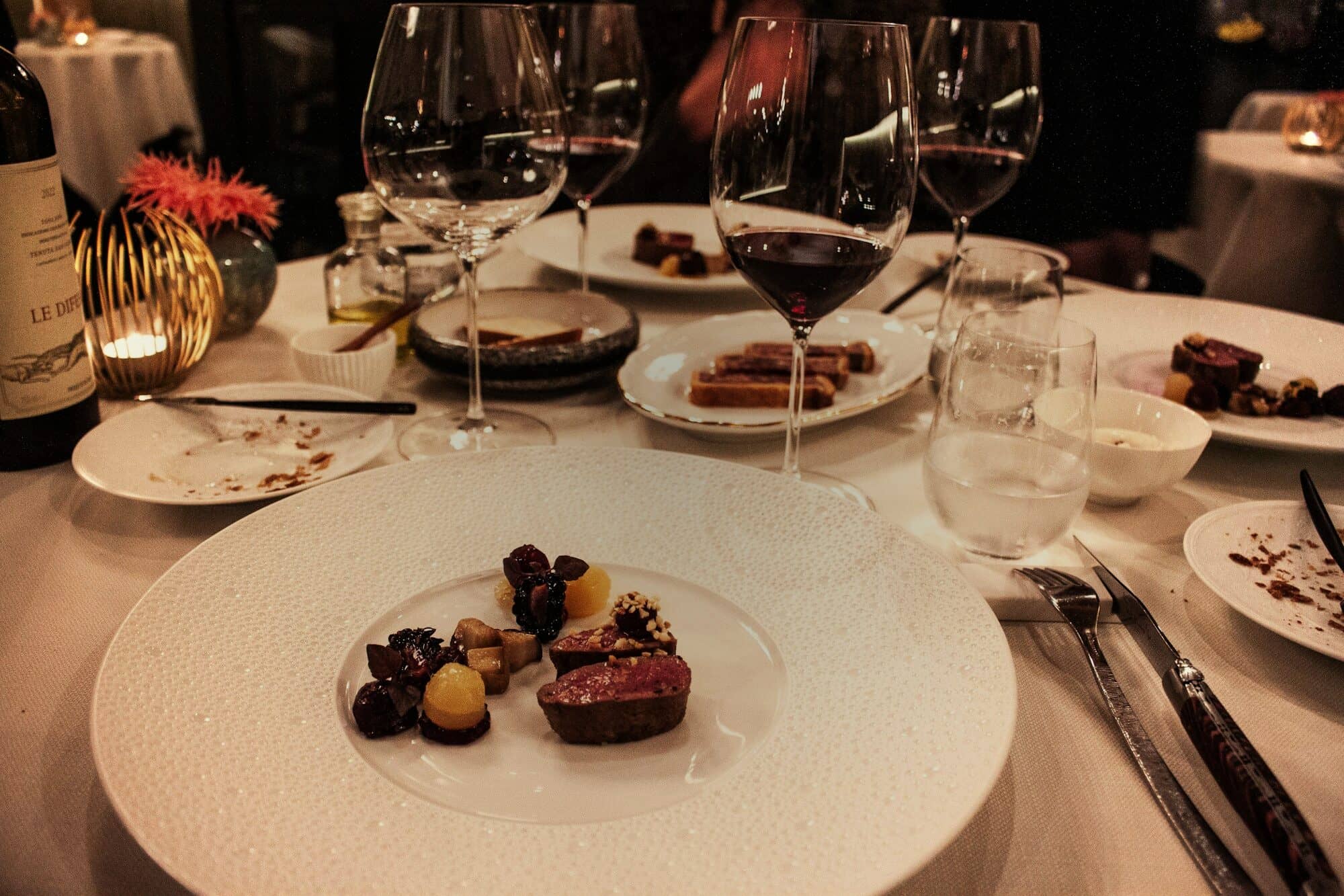 A plated course beside wine glasses on a white tablecloth